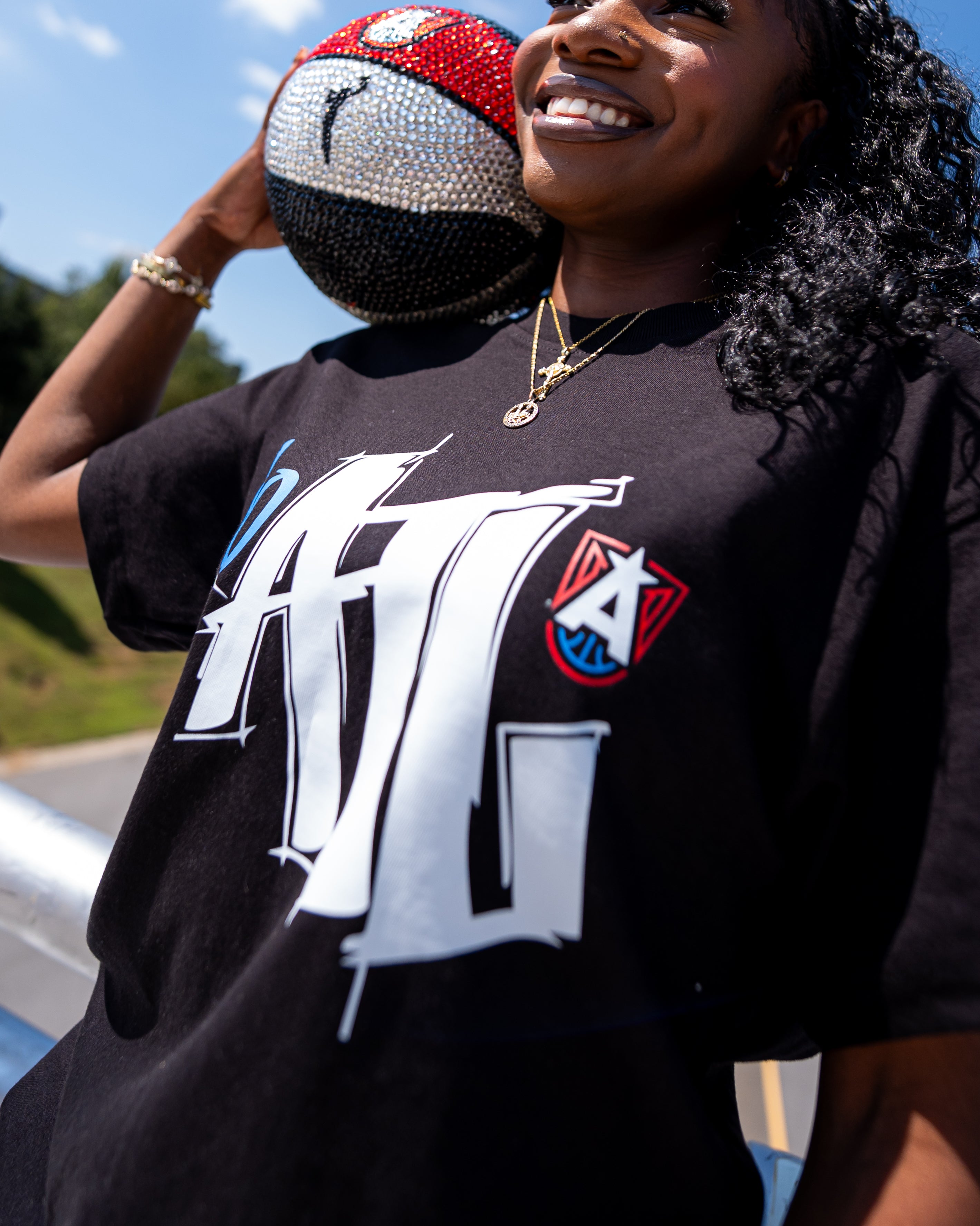 Woman wearing a black t-shirt with a ATL graffiti logo, holding a rhinestone-encrusted Dream basketball