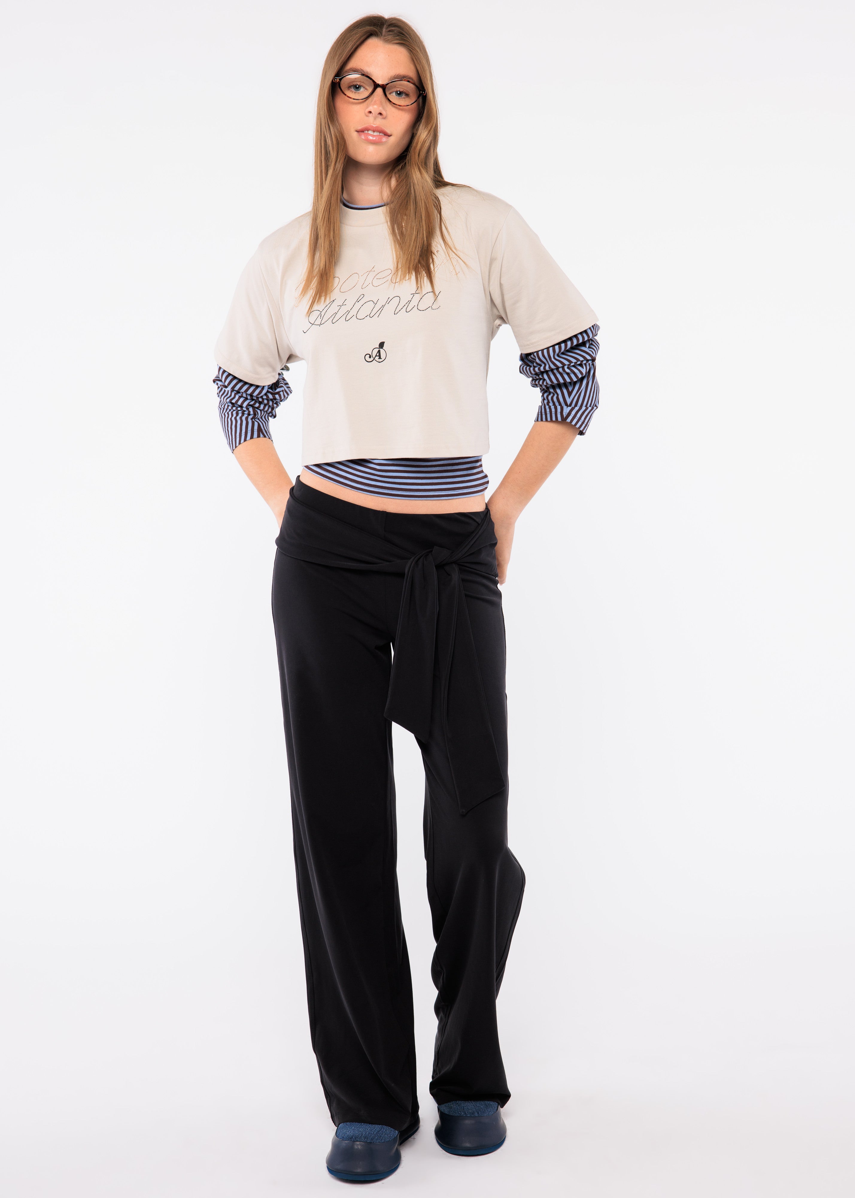 Woman wearing a white sweater with blue accents and black pants