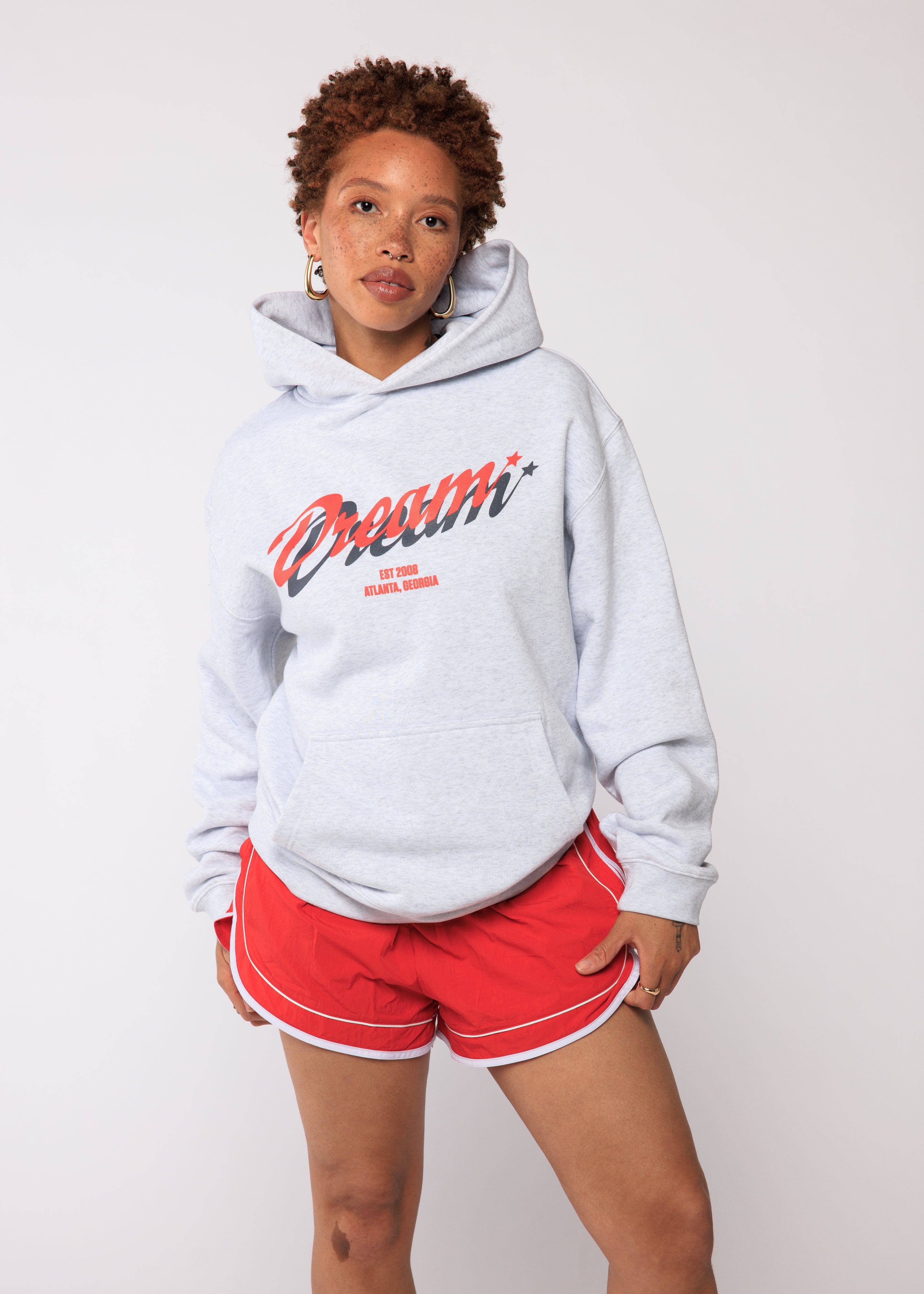 Person wearing a gray hoodie with red text and red shorts