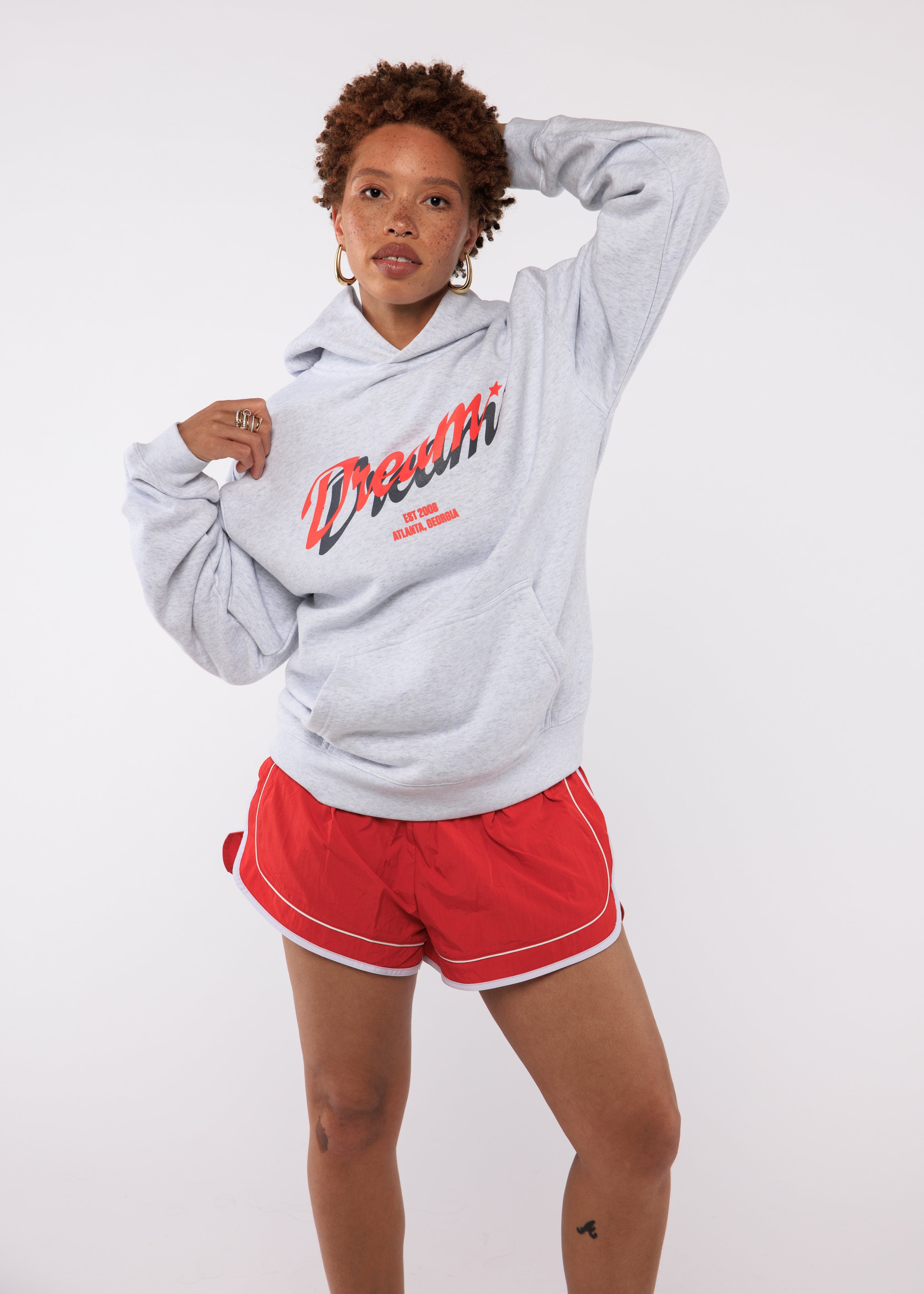 Person wearing a gray hoodie with red text and red shorts