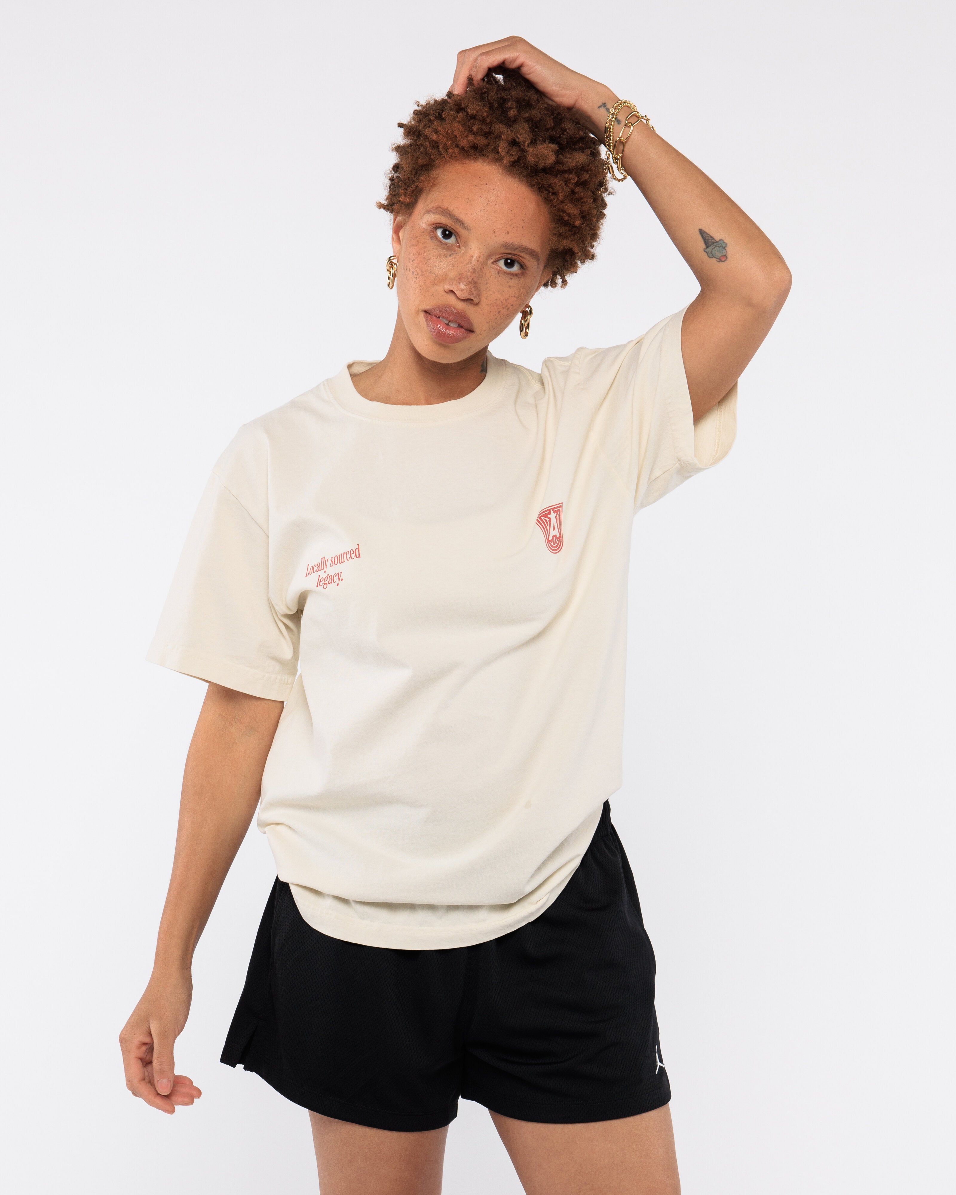 Person wearing a beige t-shirt with text and black shorts