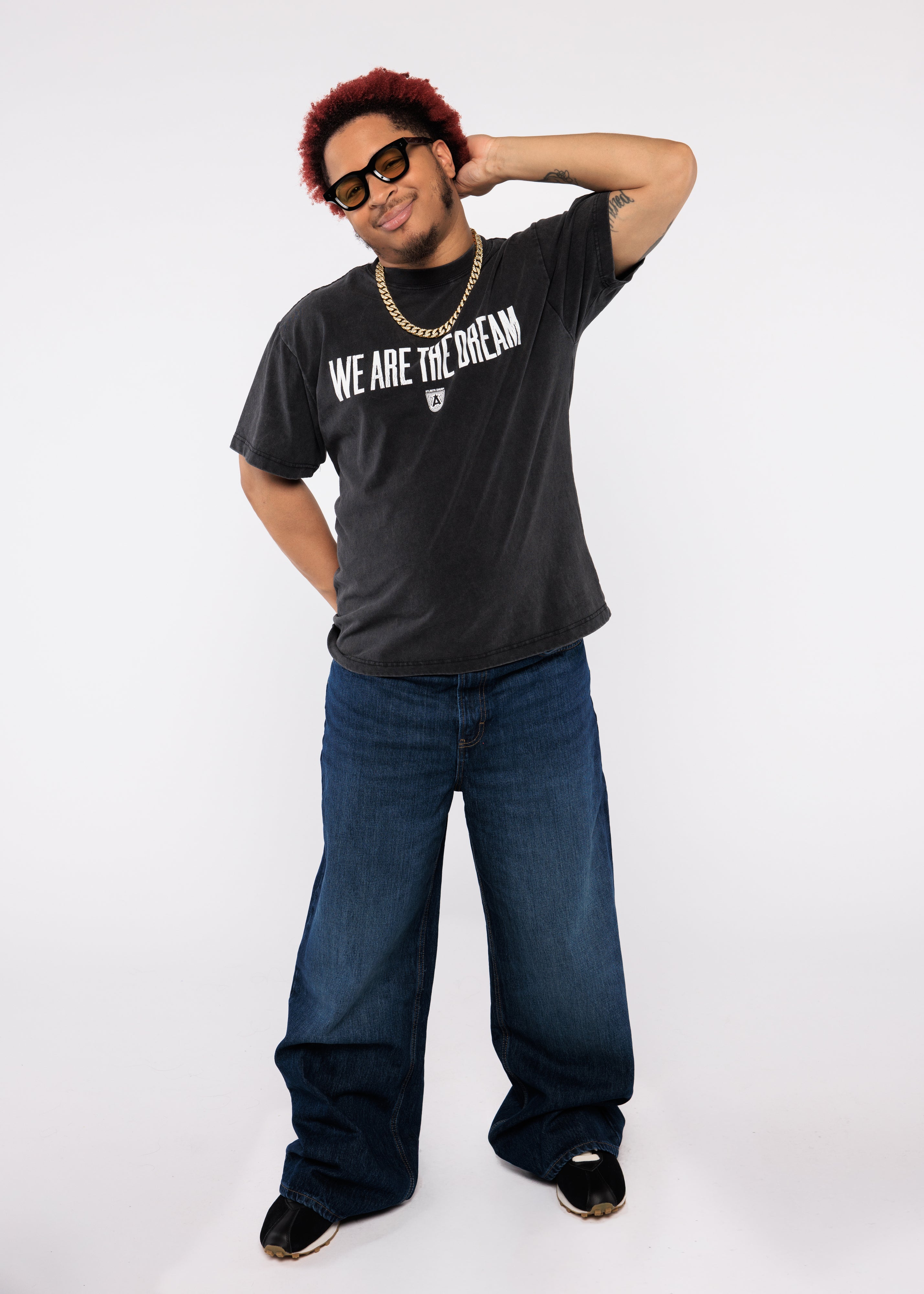 Wearing a black t-shirt with 'We Are the Dream' text and blue jeans
