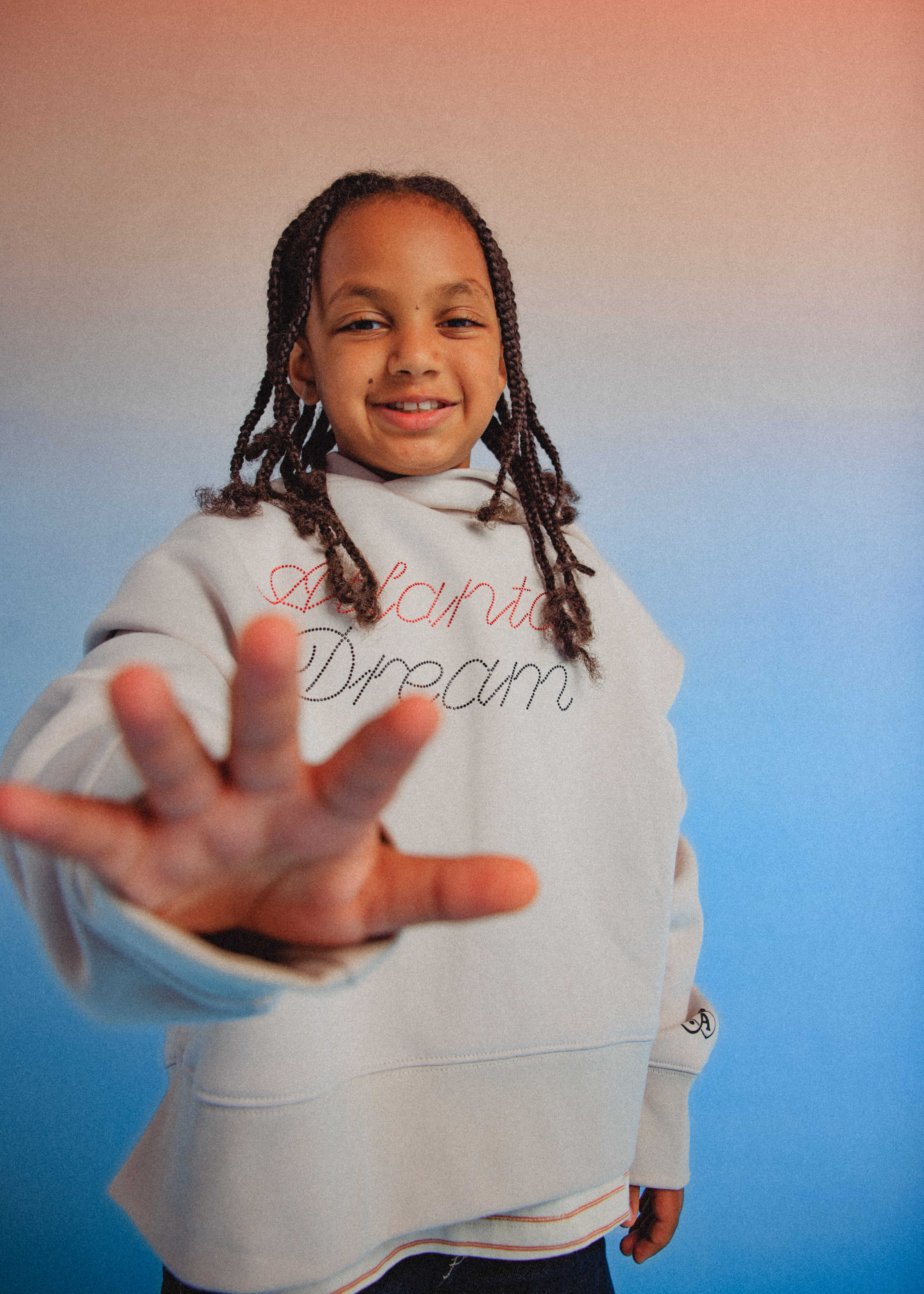 Child wearing a hoodie with 'Children's Dream' text, reaching out with hand 