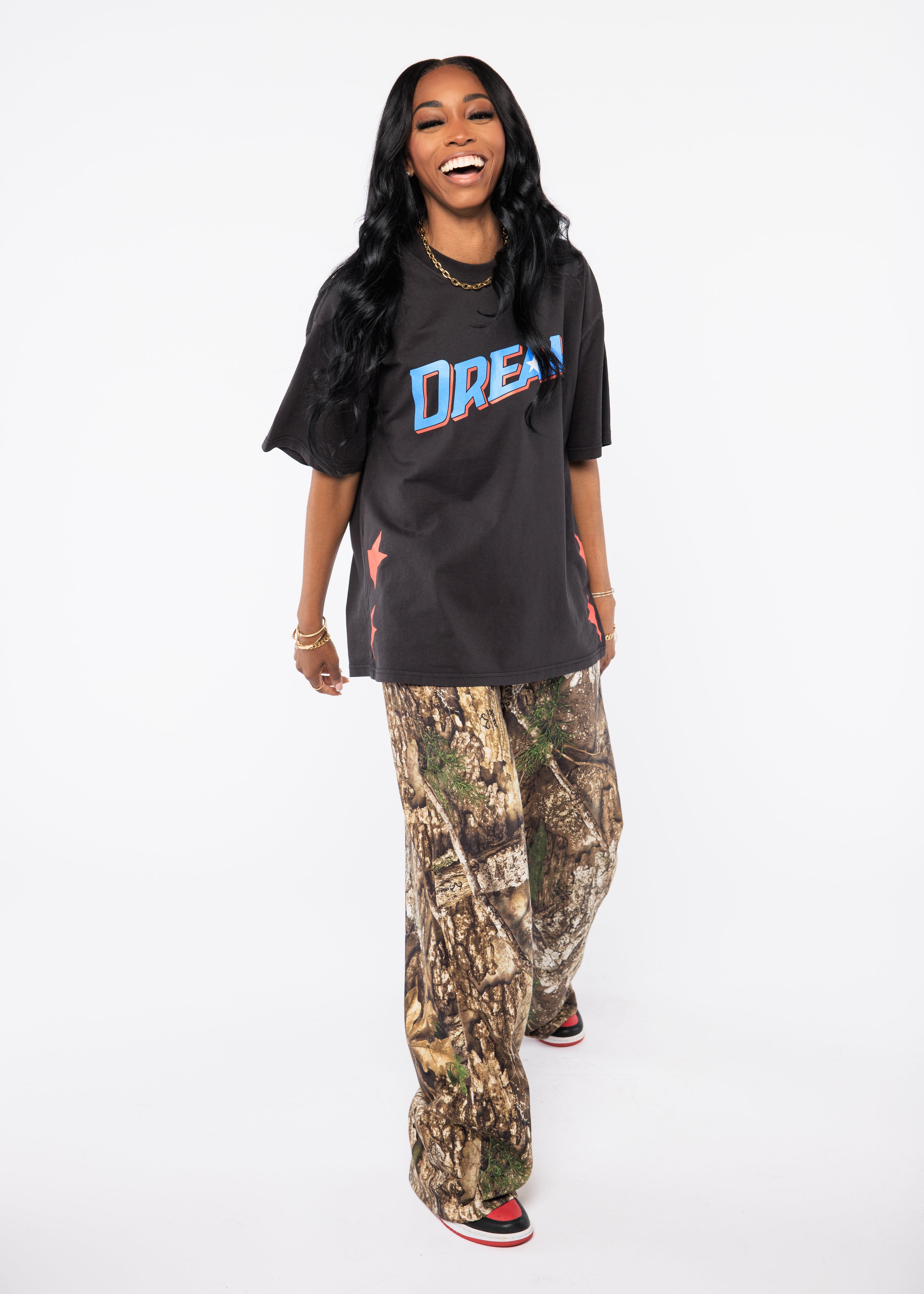 Wearing a black t-shirt with 'DREAM' printed on it and camouflage pants 