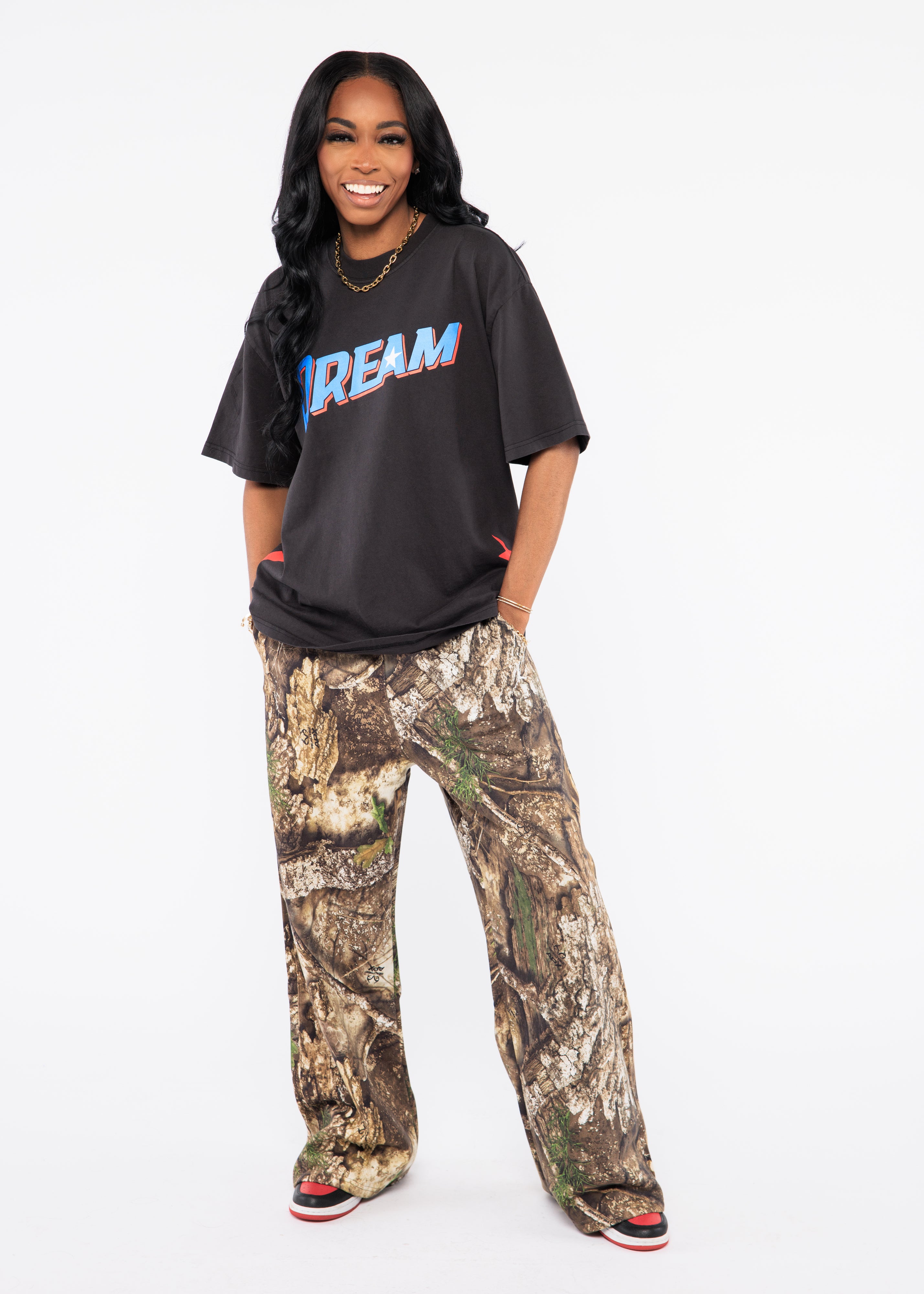 Wearing a black t-shirt with colorful text and camouflage pants