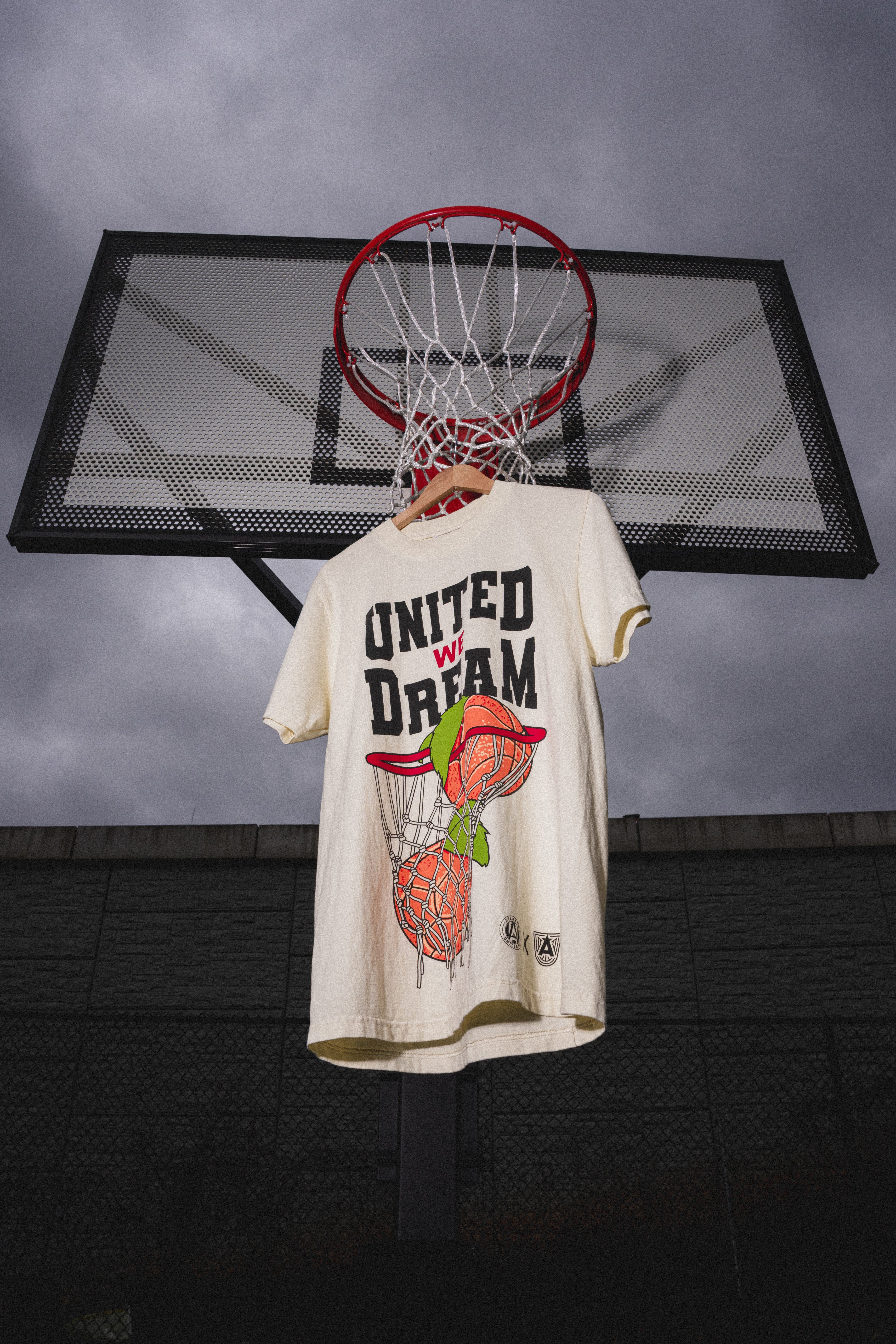T-shirt with 'United We Dream' design hanging from a basketball hoop