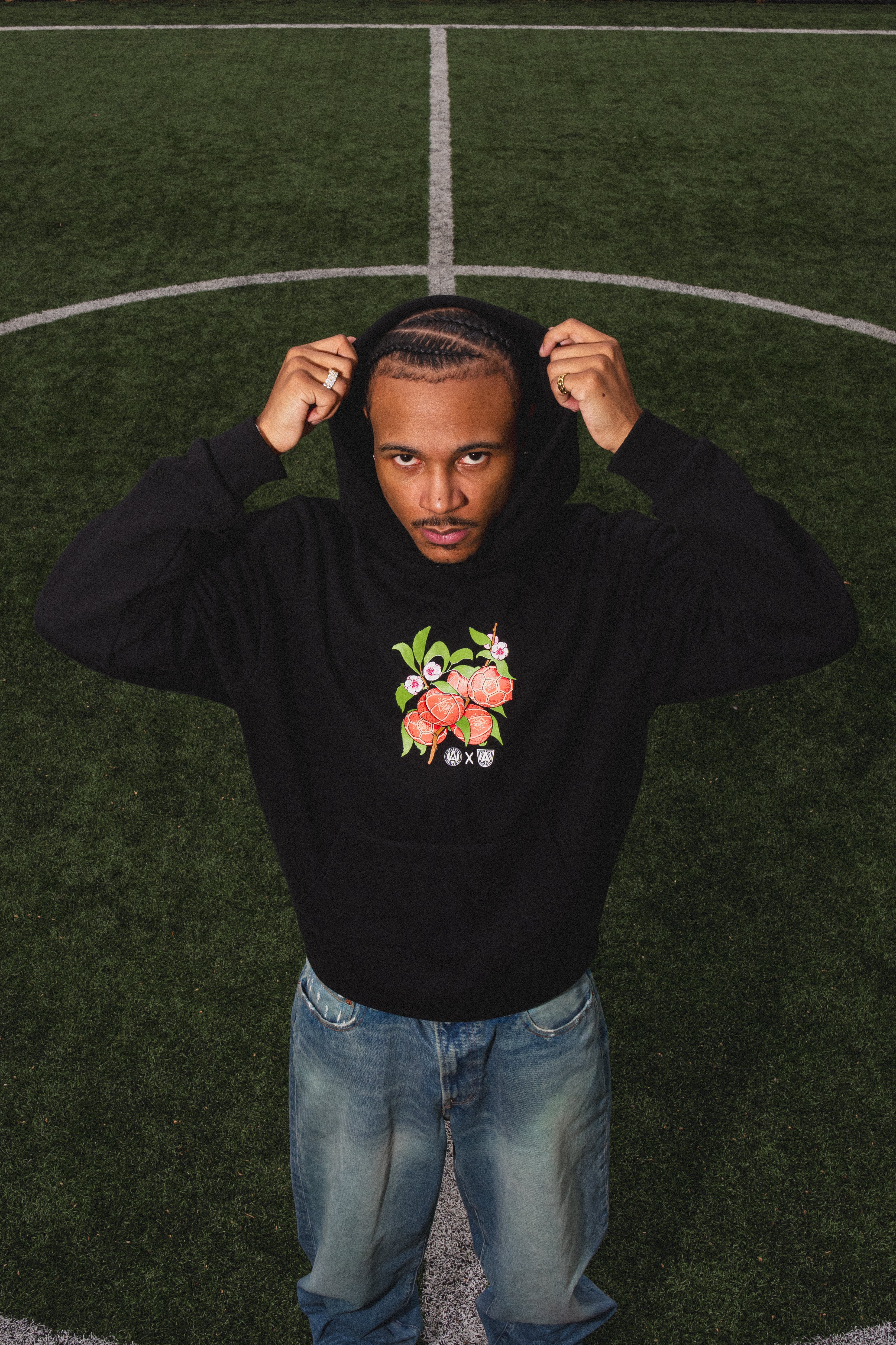 Person wearing a black hoodie with a floral design on a grassy field