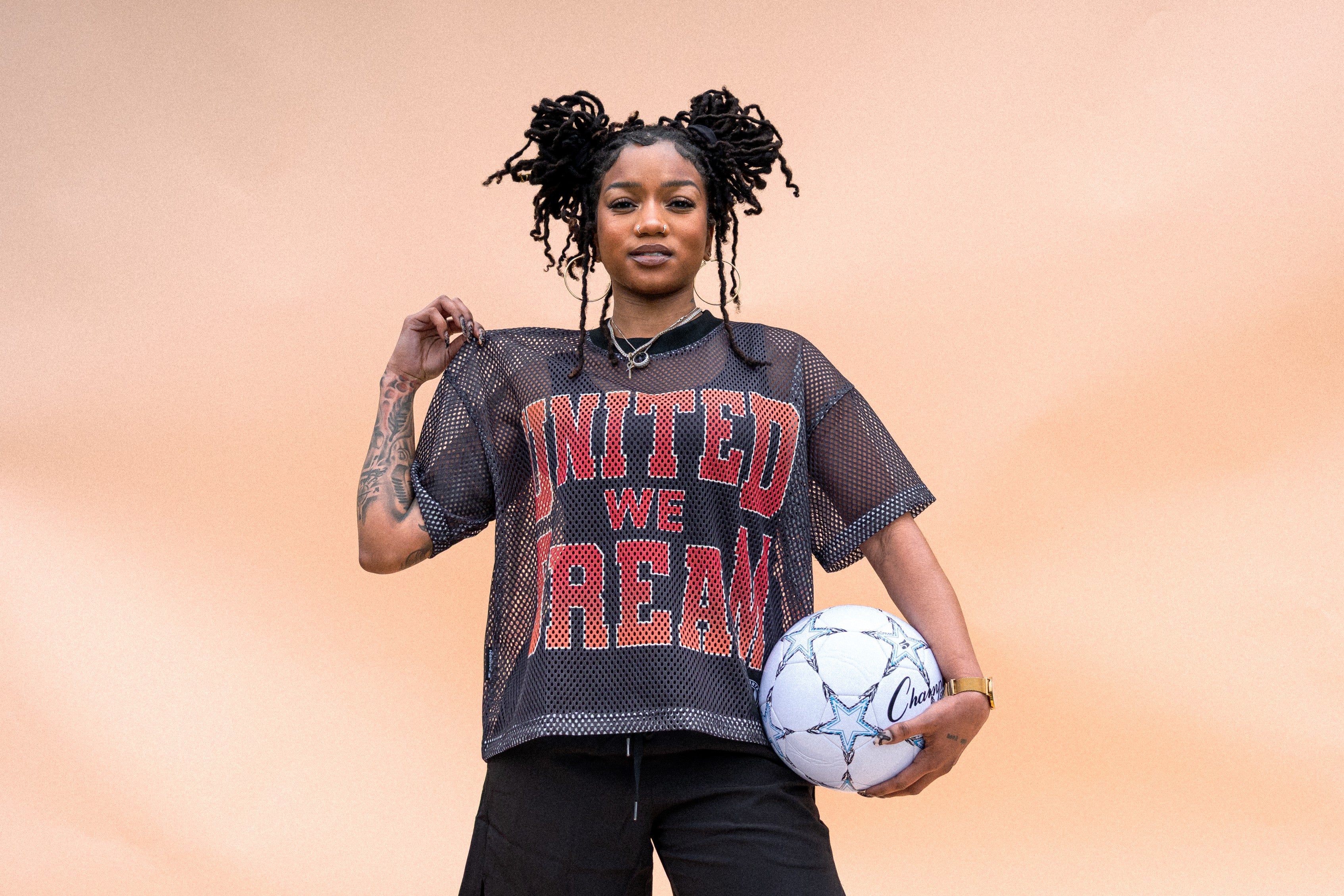 Person wearing a 'United We Dream' shirt holding a soccer ball 