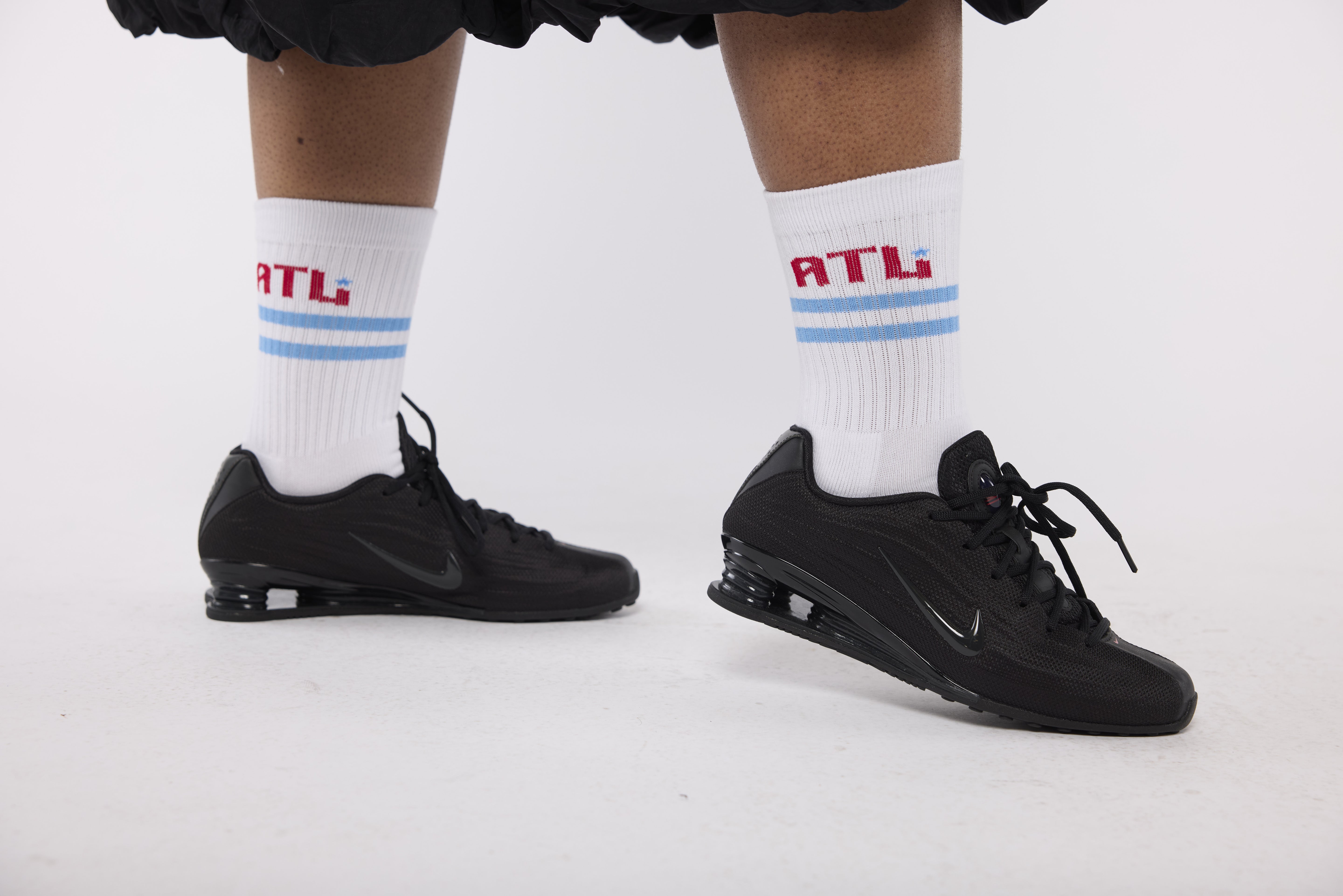 Black athletic shoes with white socks featuring 'ATL' 