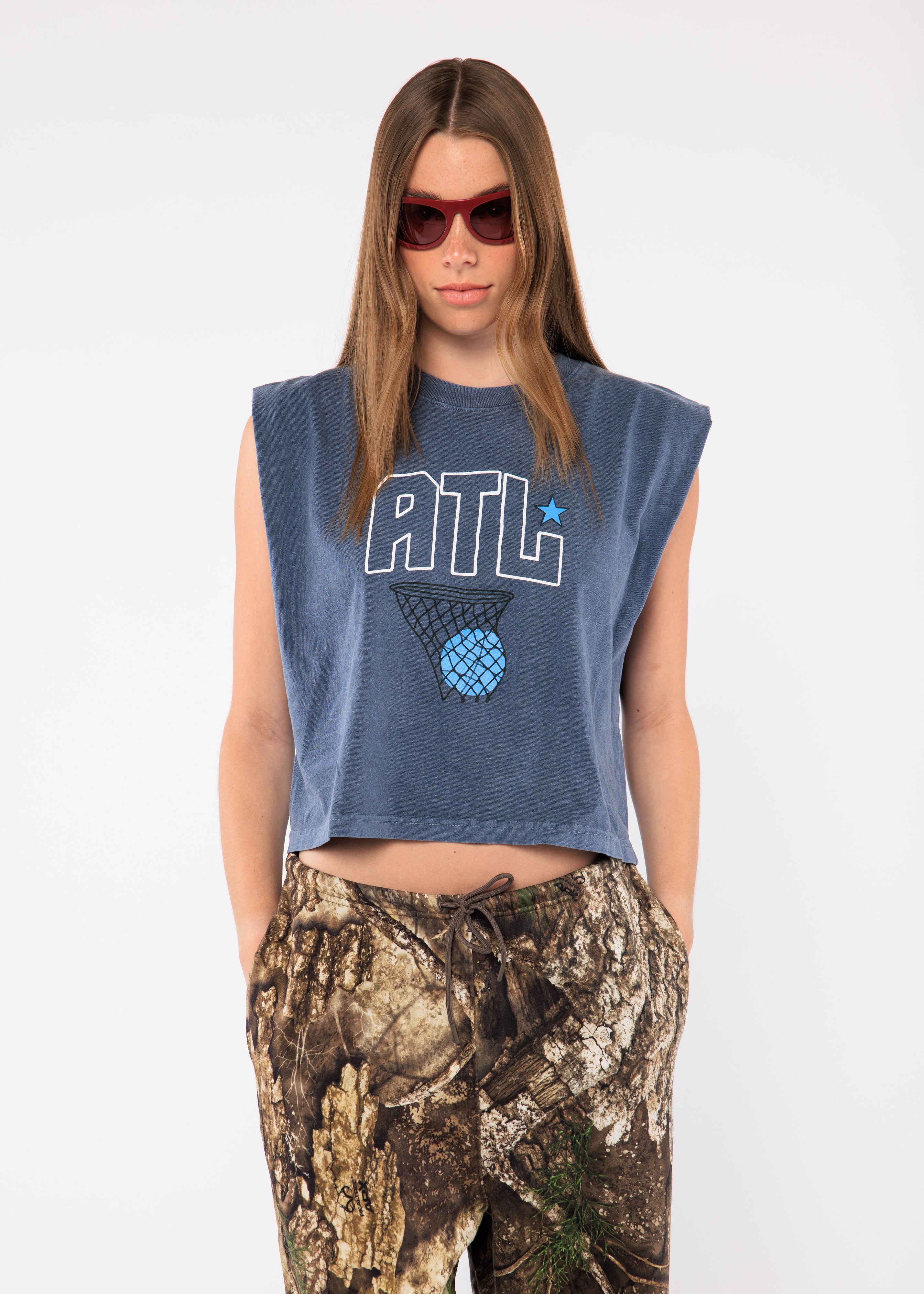 Person wearing a sleeveless blue top with 'ATL' and camouflage pants 